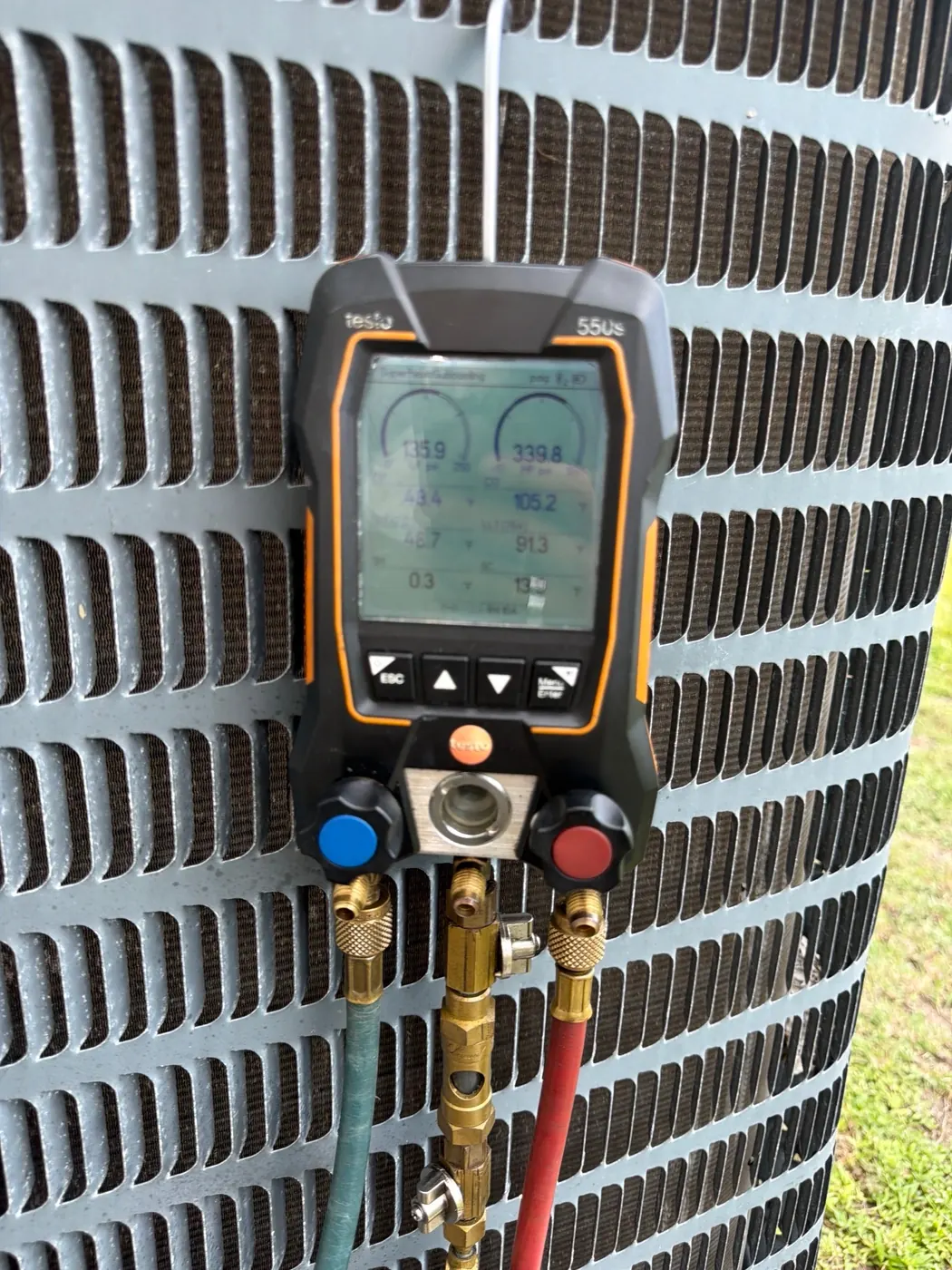 Digital HVAC gauges connected to condenser
