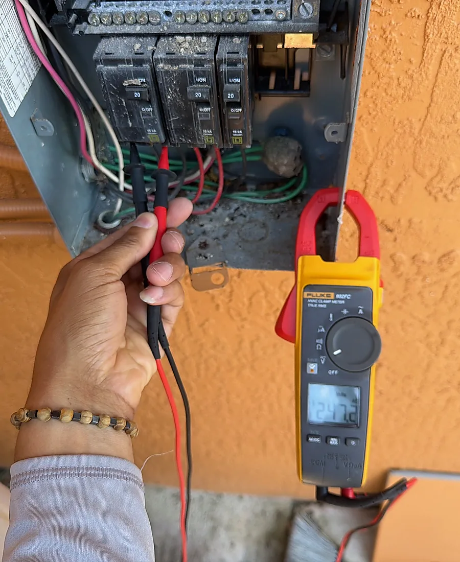 Technician testing a breaker panel with a Fluke clamp meter