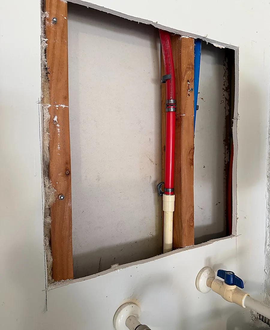 Wall opened to access and repair a PEX water line